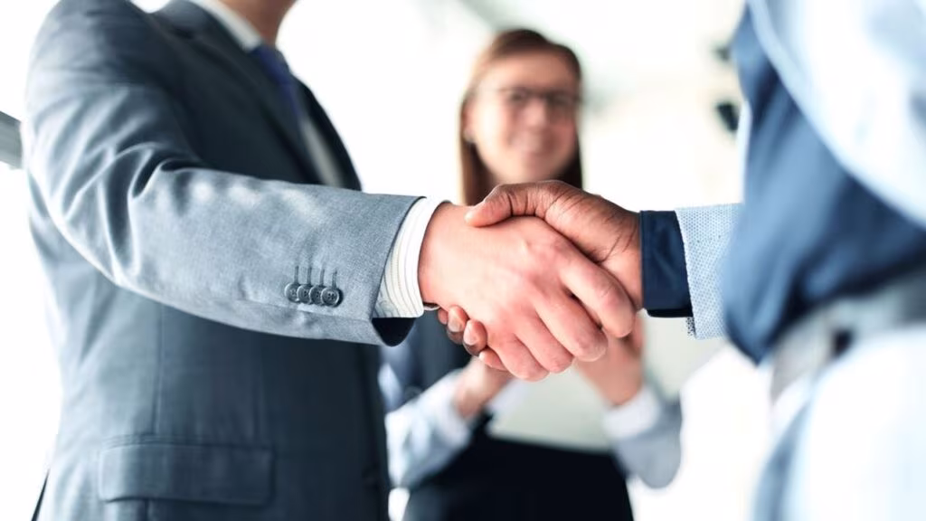 Poignée de main entre un dirigeant et son successeur symbolisant la réussite d'une transmission d'entreprise familiale sécurisée par le Pacte Dutreil 2026.