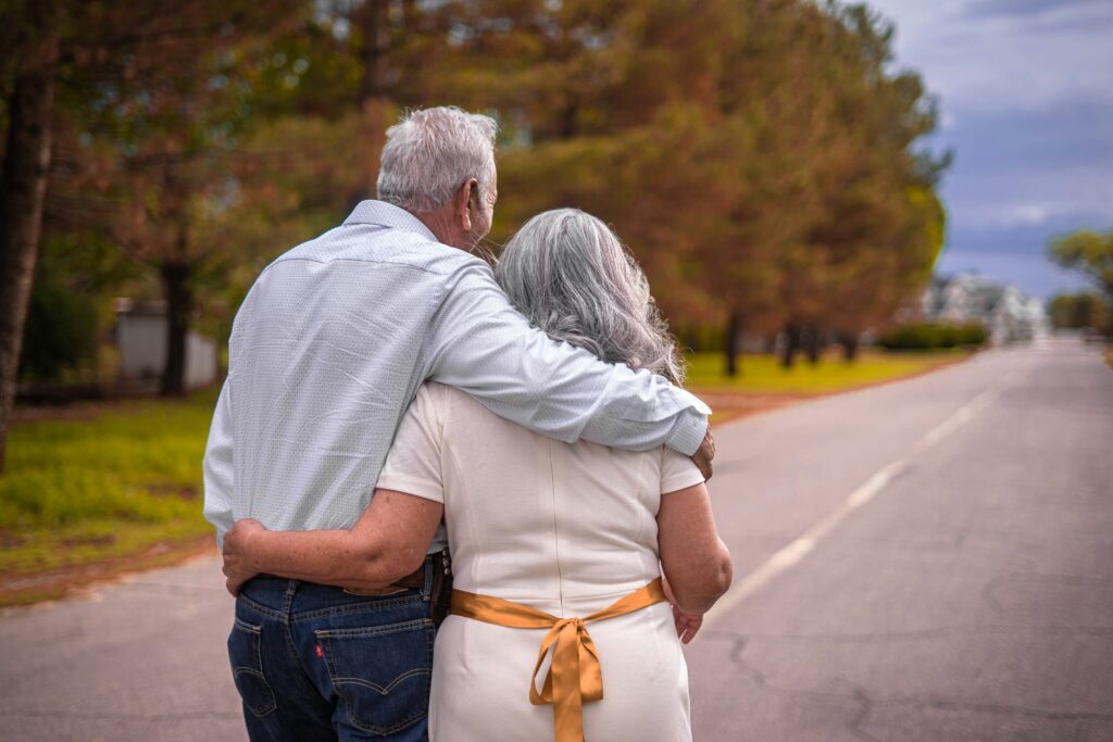 Un couple de retraités, vus de dos, marche bras dessus bras dessous sur une route menant vers l'horizon, illustrant la sérénité et la planification financière à long terme pour la retraite.