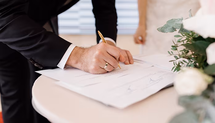 Signature d'un contrat de mariage sous le régime de la séparation de biens par un marié portant une alliance, scellant l'indépendance financière des époux.